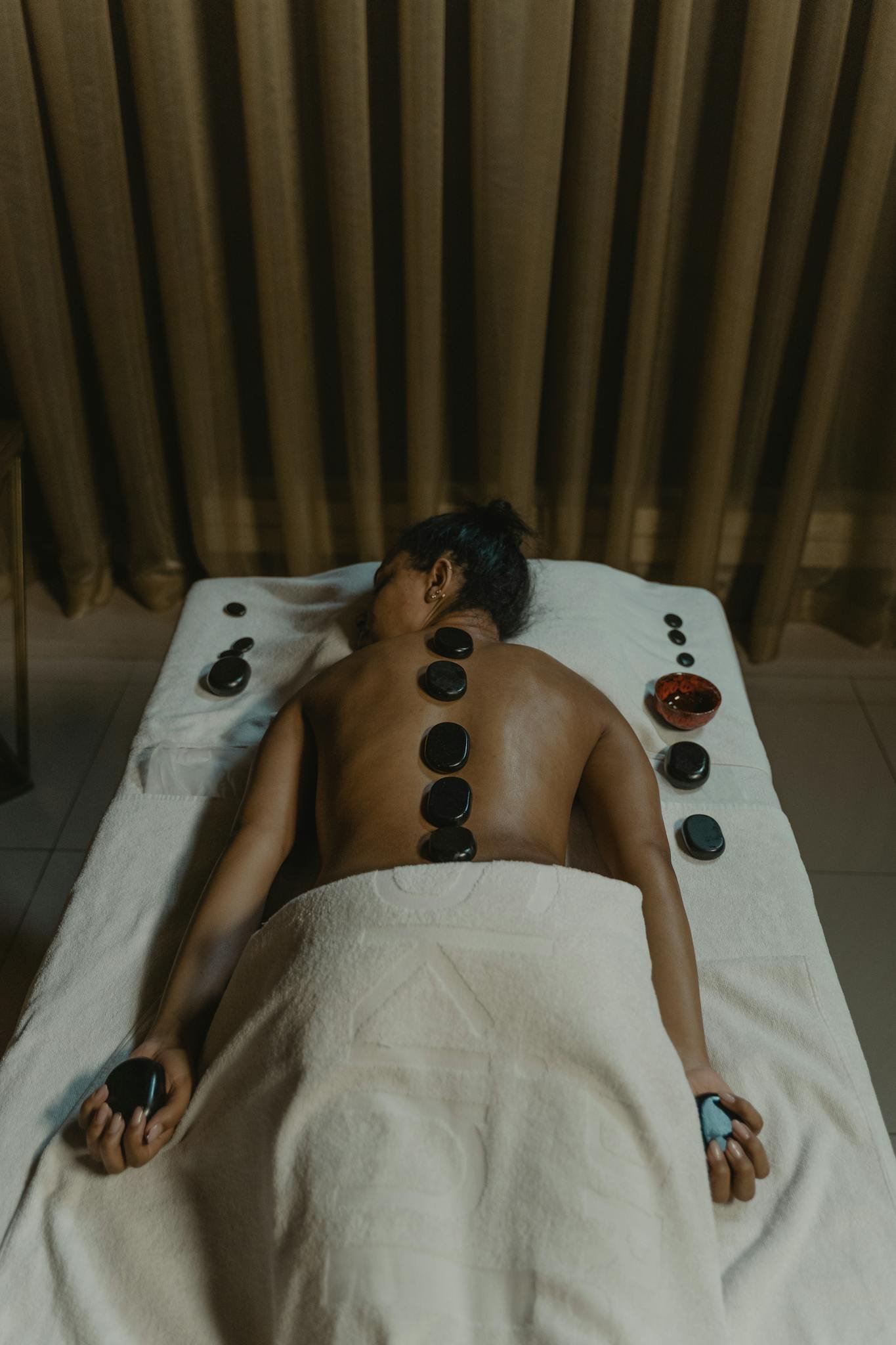 Woman enjoying a soothing hot stone massage in a tranquil spa setting.